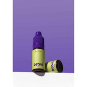 A bottle of Brovi One e-liquid in the 'dark brown' flavor, standing upright next to its cap on a white surface against a solid purple background.
