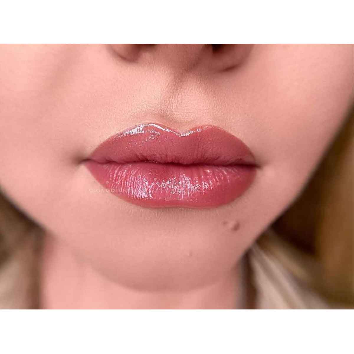 Close-up of a person's lips wearing a glossy, dusty rose pink lip gloss or lipstick.