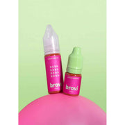 Two small Brovi e-liquid bottles on a pink rounded surface against a pale green background. One bottle has a white cap and the other has a light green cap, both with bright pink labels reading 'salted caramel' and 'brovi'.