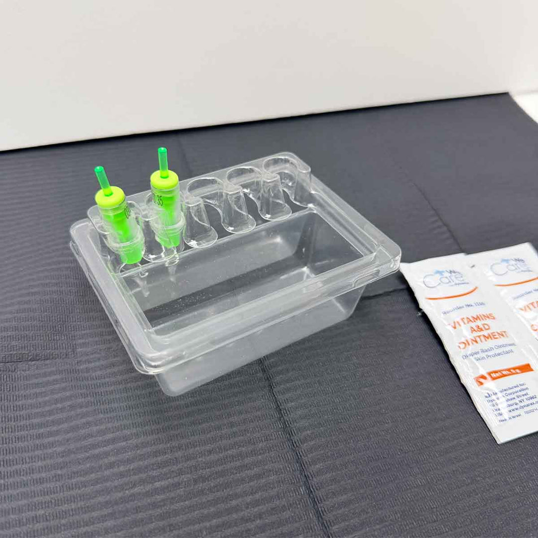 tattoo cartridge tray with green cartridge needles on a gray surface next to a white packet.
